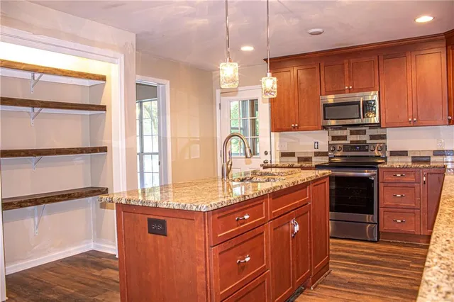 a kitchen with stainless steel appliances granite countertop a stove a sink and a microwave