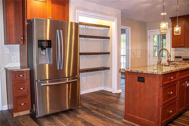 a kitchen with stainless steel appliances granite countertop a refrigerator and a wooden floor
