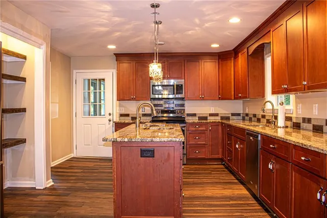 a kitchen with kitchen island granite countertop wooden cabinets and a stove