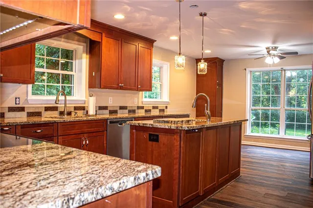 a kitchen with stainless steel appliances granite countertop wooden cabinets a window and a sink