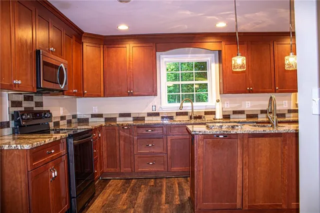 a kitchen with stainless steel appliances granite countertop wooden cabinets a stove and a sink