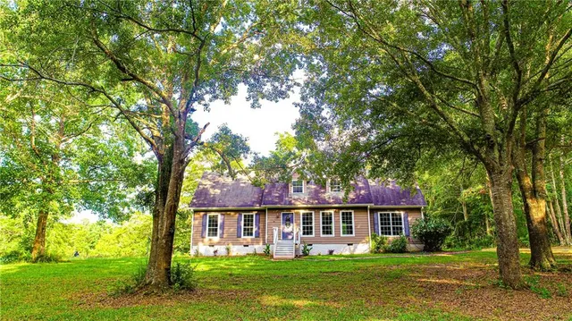 a front view of a house with a garden and trees