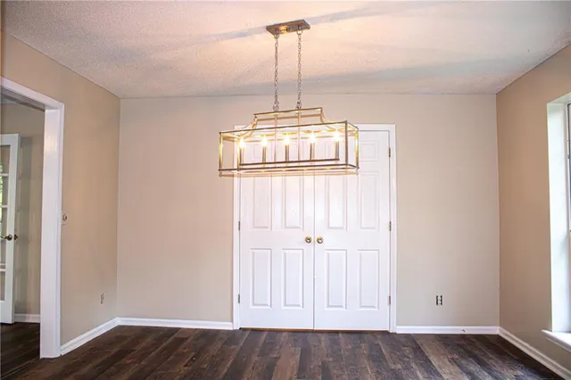 a view of an empty room with wooden floor and window