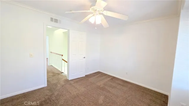 an empty room with a chandelier fan and windows