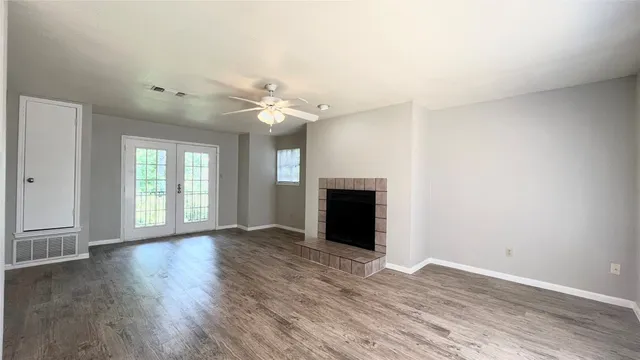 a view of an empty room with a window and wooden floor