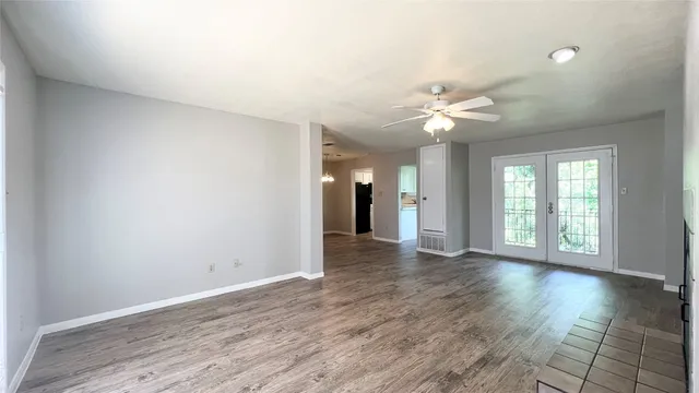a view of an empty room with window and wooden floor