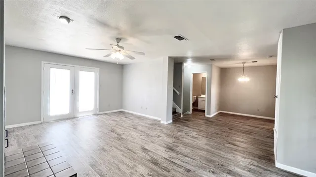 a view of an empty room with window and wooden floor