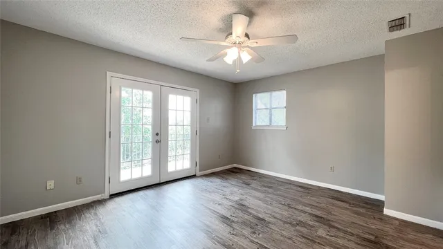 an empty room with wooden floor fan and windows