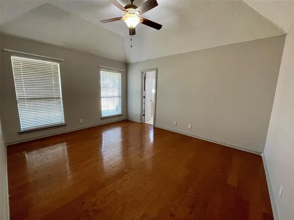 an empty room with wooden floor chandelier fan and windows