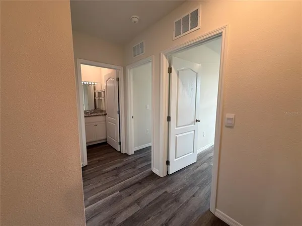 a view of a hallway with wooden floor and a living room