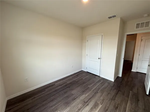 a view of an empty room with wooden floor and closet