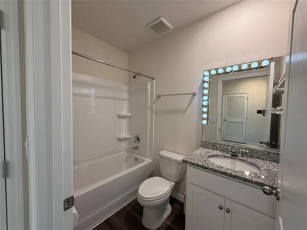 a bathroom with a granite countertop toilet a sink and a bathtub