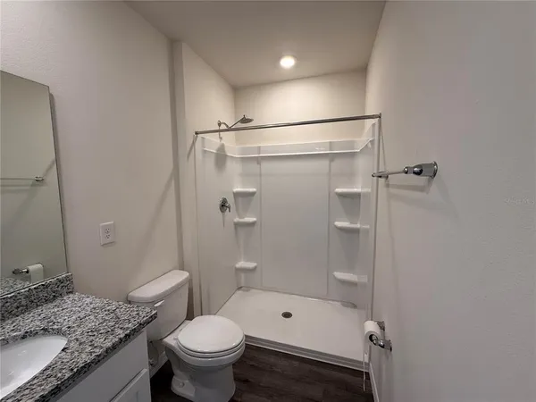a bathroom with a granite countertop sink toilet and shower