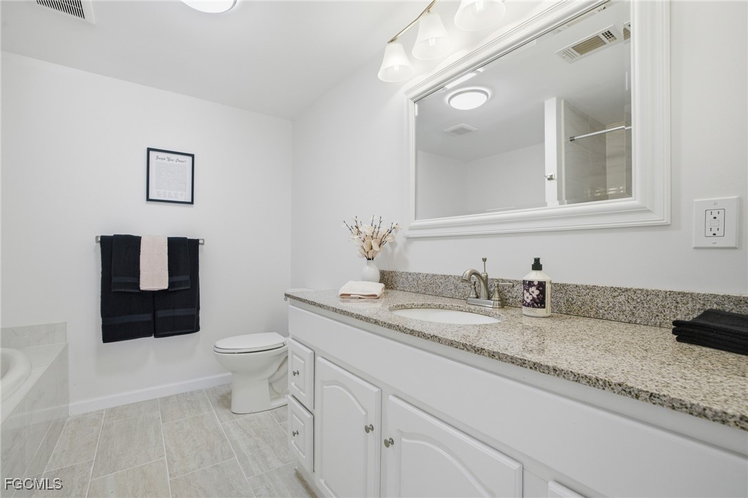 14736 Patrick Henry Road North Fort Myers, FL 33917 - Photo 17 of 47 a bathroom with a granite countertop toilet sink and mirror