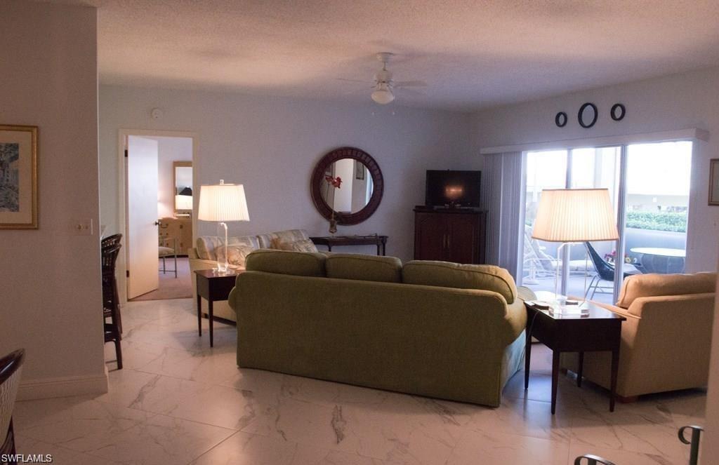 5817 Glencove Drive, Unit 404 Naples, FL 34108 - Photo 4 of 21 a living room with furniture a window and a lamp