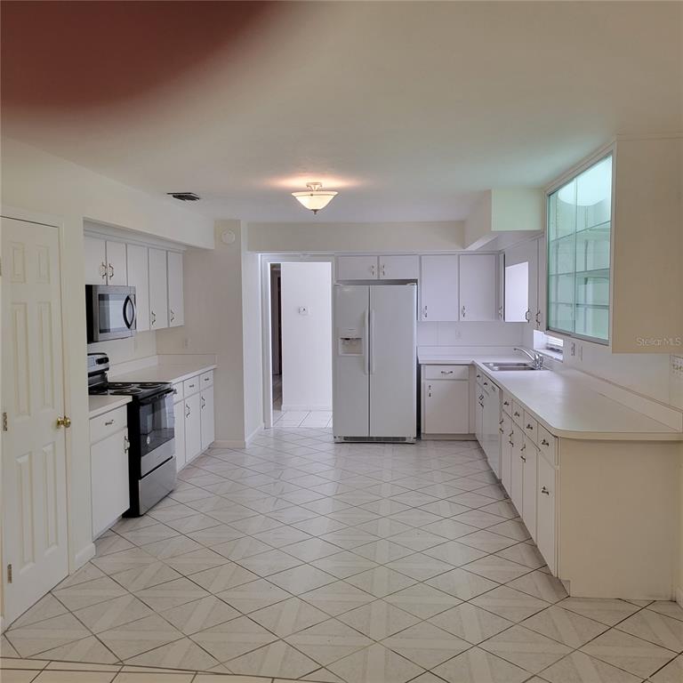 1661 Votaw Road Apopka, FL 32703 - Photo 8 of 23 a large kitchen with a stove a sink dishwasher a refrigerator and white cabinets with wooden floor