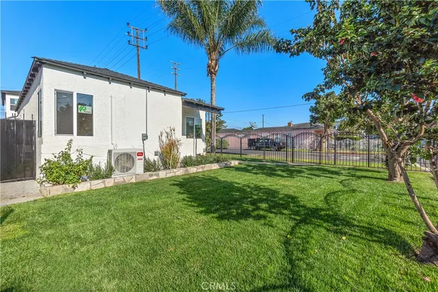 a backyard of a house with table and chairs plants and large tree
