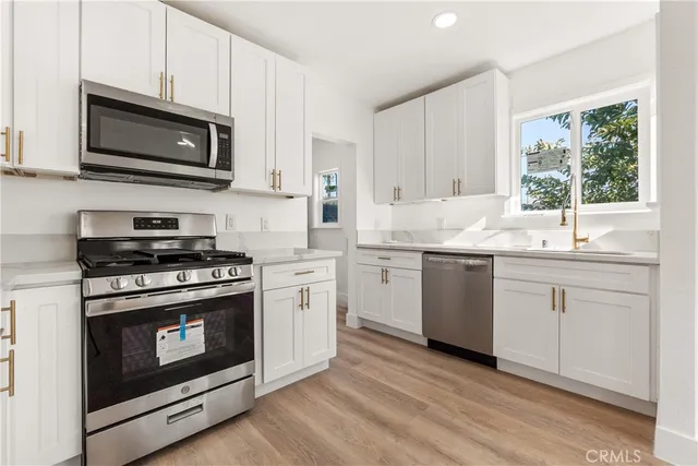 a kitchen with stainless steel appliances granite countertop a sink a stove a microwave and wooden cabinets