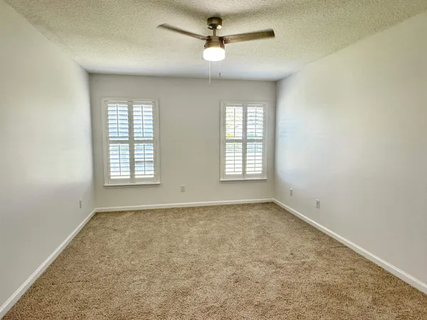 an empty room with windows and fan