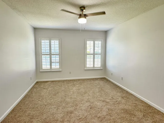an empty room with windows and fan