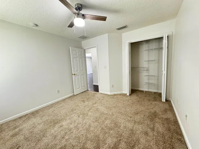 an empty room with closet and a ceiling fan