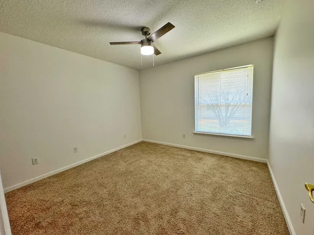 an empty room with a chandelier fan and windows