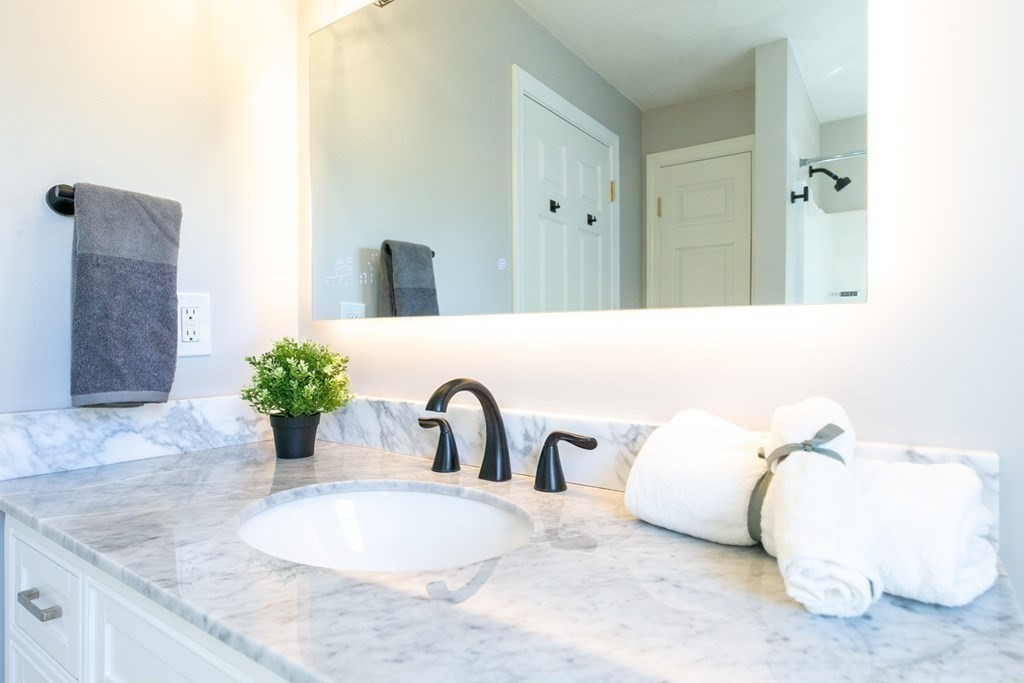 6 King Street Arlington, MA 02474 - Photo 23 of 37 a bathroom with a granite countertop sink a mirror and vanity