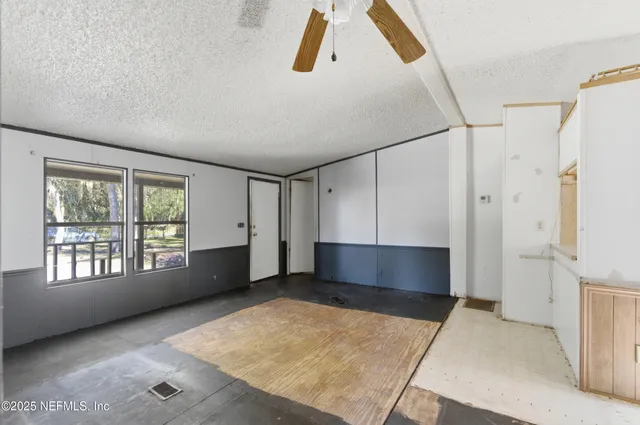 a view of an empty room with a window and a kitchen