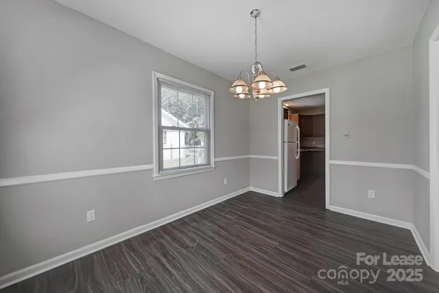 a view of a room with wooden floor chandelier and a window