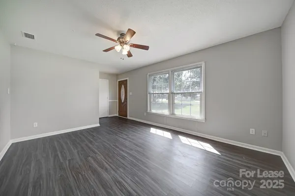 a view of empty room with wooden floor and fan