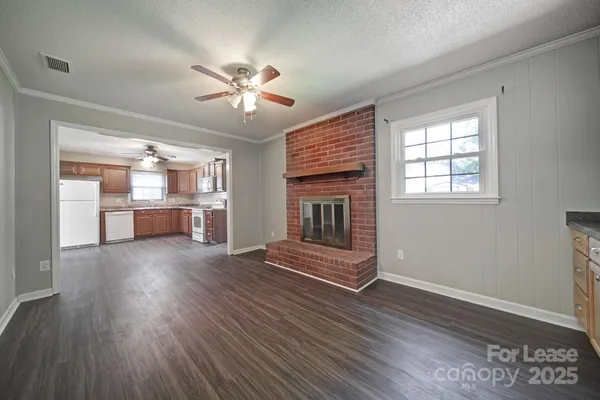 a view of a livingroom with wooden floor a ceiling fan and windows