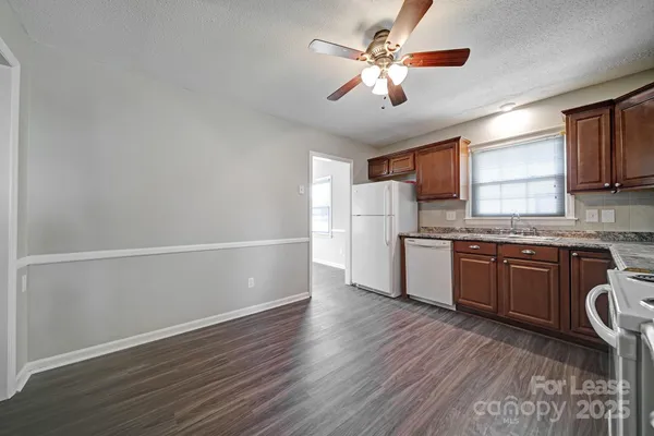 a kitchen with granite countertop a refrigerator cabinets and wooden floor