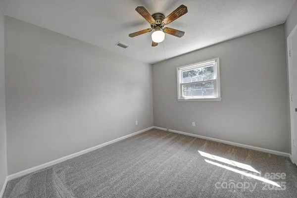 an empty room with a window and a fan