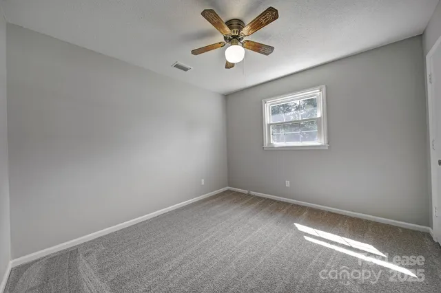 an empty room with a window and a fan