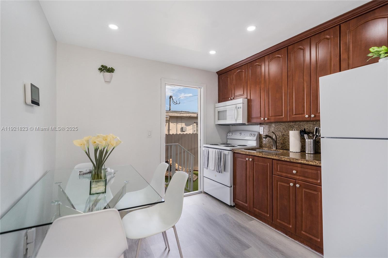 4421 Northwest 9th Street, Unit 4421 Miami, FL 33126 - Photo 4 of 14 a kitchen with stainless steel appliances granite countertop a refrigerator a stove top oven a sink with island and chairs