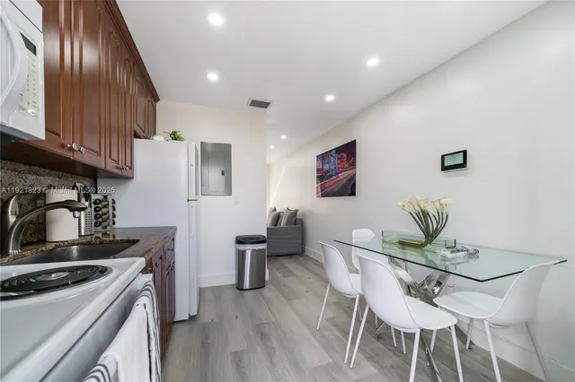 a kitchen with stainless steel appliances granite countertop a stove top oven a sink dishwasher and white cabinets with wooden floor