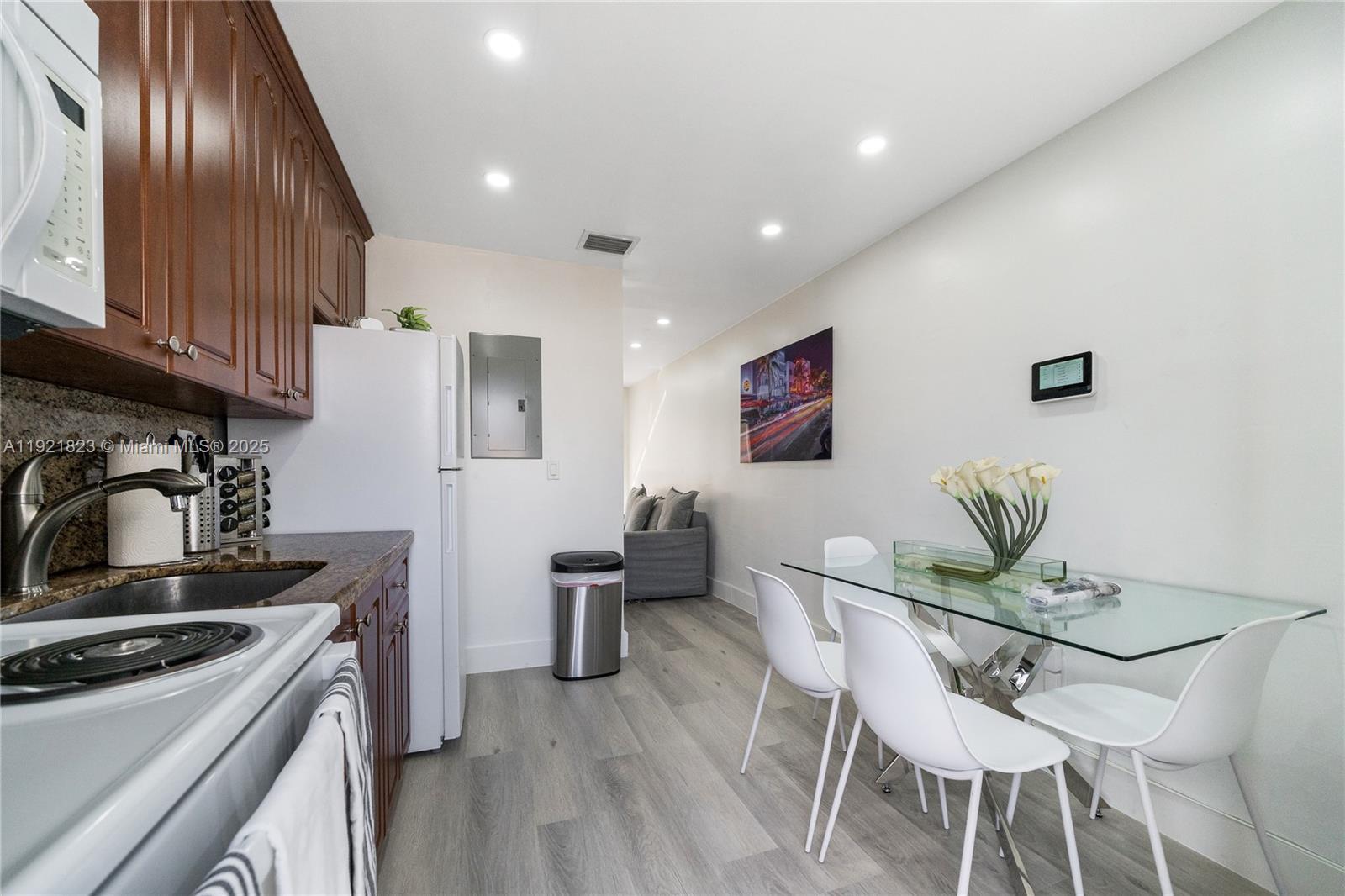 4421 Northwest 9th Street, Unit 4421 Miami, FL 33126 - Photo 5 of 14 a kitchen with stainless steel appliances granite countertop a stove top oven a sink dishwasher and white cabinets with wooden floor