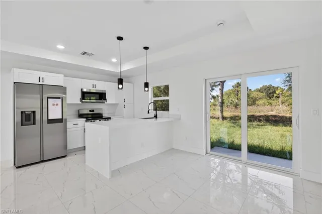 a view of kitchen with stainless steel appliances kitchen island refrigerator sink and stove