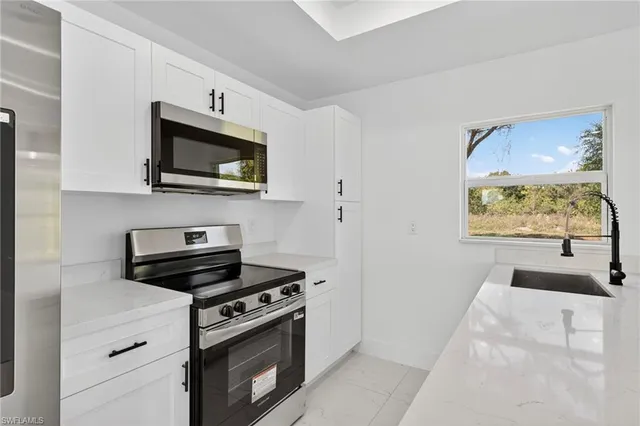 a kitchen with stainless steel appliances a stove microwave and sink