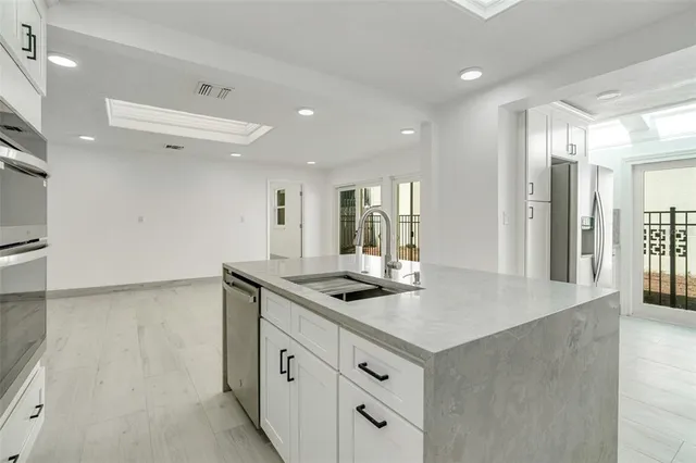 a kitchen with granite countertop a sink and white cabinets with wooden floor