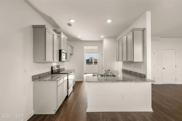 a view of a kitchen with a sink and dishwasher a refrigerator with wooden floor