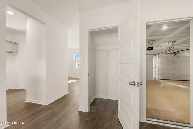 a view of an empty room with wooden floor and stairs