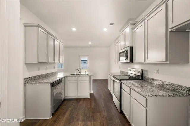 a kitchen with granite countertop white cabinets white stainless steel appliances and a sink