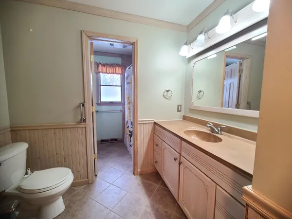 a bathroom with a granite countertop sink toilet and mirror