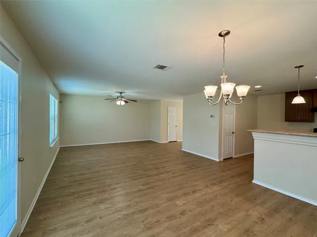 a view of a room with a hanging light and kitchen view