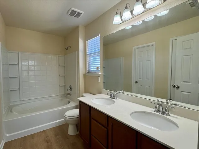 a bathroom with a double vanity sink a toilet a bathtub and shower