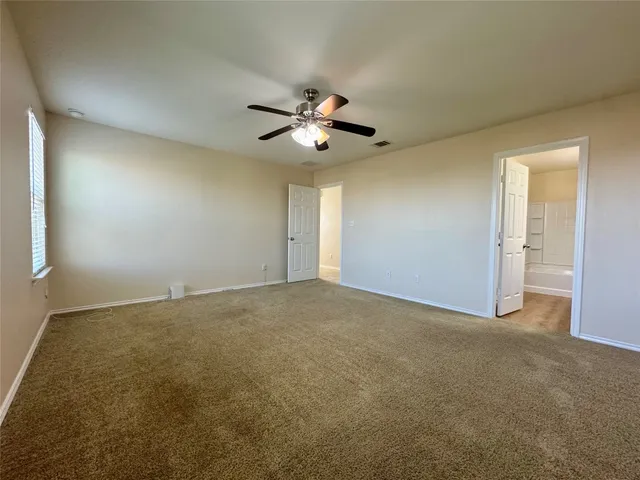 a view of a room with a ceiling fan and carpet