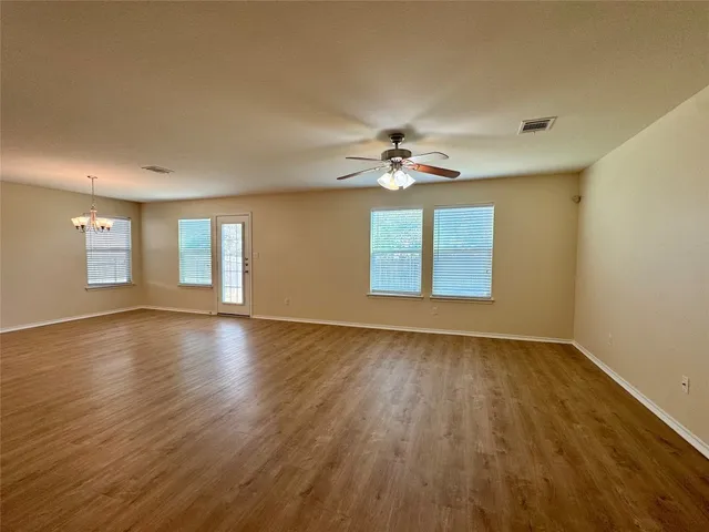 a view of an empty room with a window and wooden floor