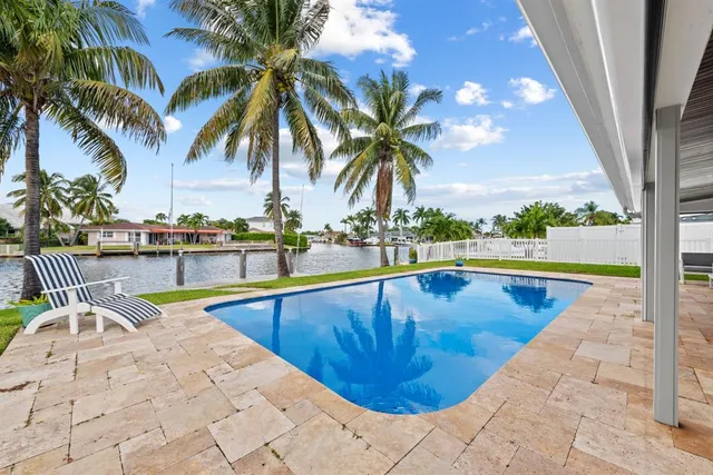 a view of a swimming pool with a lawn chairs under palm trees