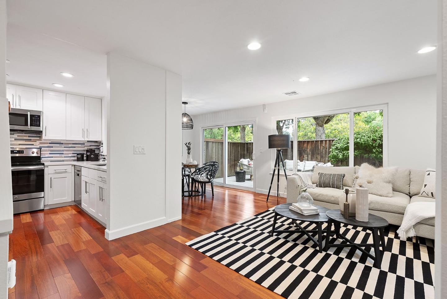 a living room with furniture a large window and wooden floor